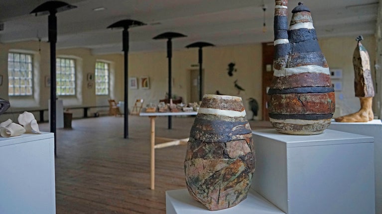 A set of vases sits in the foreground set in a large historic room